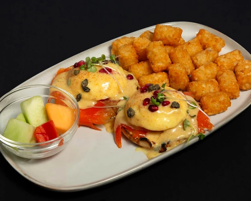 Smoked salmon eggs Benedict with hollandaise, tater tots and fresh fruit at Rise & Dine Calgary SE